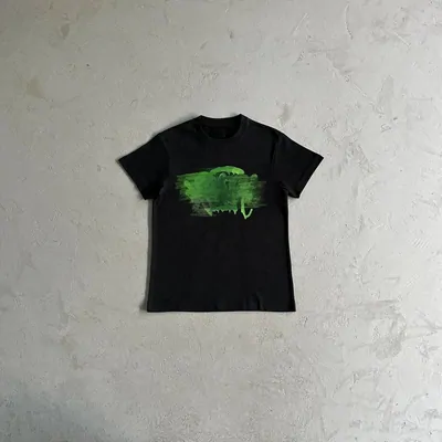 A black tee with short sleeves, spread on pale plaster and printed with a single green brushstroke
